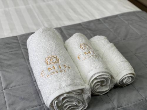 three white towels sitting on top of a bed at Emin hotel in Fergana