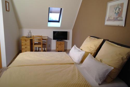 a bedroom with a bed with pillows and a television at Heidehotel Jagdhof Dobra GmbH in Dobra