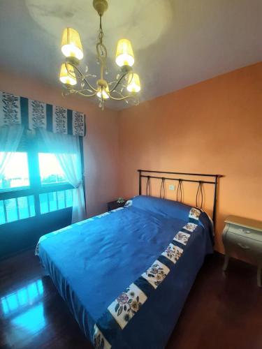 Schlafzimmer mit einem blauen Bett und einem Kronleuchter in der Unterkunft Loyos - Playa Grande Miño in Miño