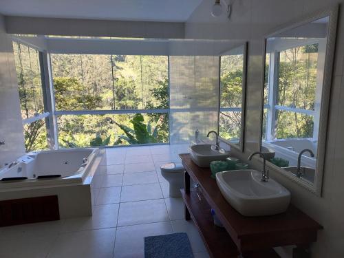 a bathroom with two sinks and a large window at Lumiar Eco Lodge - Chalé Telhado Verde in Nova Friburgo