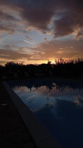 a sunset over a swimming pool with the sky at Casale Papa Country Village in Loreto