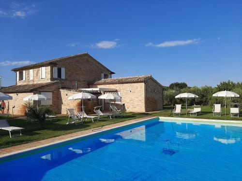 a large blue swimming pool in front of a house at Casale Papa Country Village in Loreto