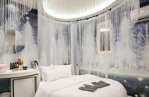 um quarto com uma cama branca e um espelho em Nine Star Hotel em Seul