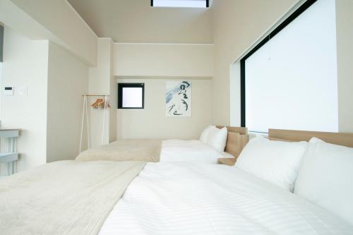 two beds in a room with a window at Ostay Ueno in Tokyo