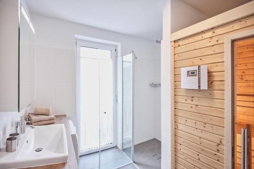 een badkamer met een witte wastafel en een douche bij die Tauplitz Lodges - Bergblick Lodge B6 by AA Holiday Homes in Tauplitz
