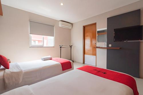 ein Hotelzimmer mit 2 Betten und einem Flachbild-TV in der Unterkunft RedDoorz Plus @ Dago Pojok 3 in Bandung