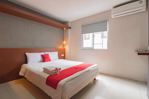 a bedroom with a large bed with a red blanket at RedDoorz Plus @ Dago Pojok 3 in Bandung