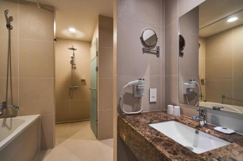 a bathroom with a sink and a shower and a tub at Hotel Square Ansan in Ansan