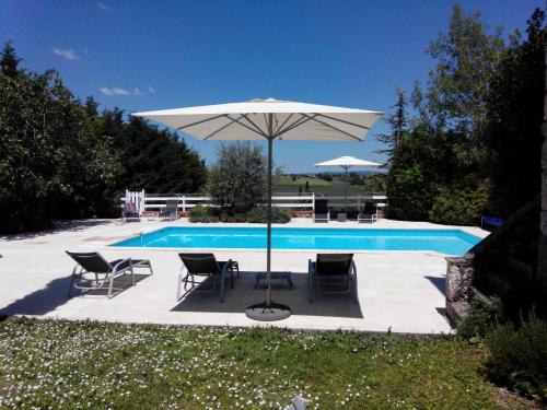 une piscine avec une table, des chaises et un parasol dans l'établissement Gites Les Vents Bleus, à Donnazac