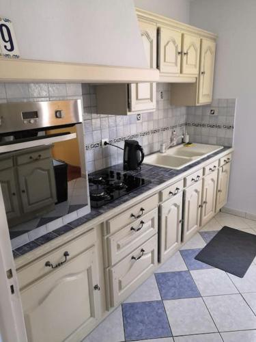 une cuisine avec des armoires blanches et un four à plaques de cuisson dans l'établissement Gîte Thomas et Joanie, à Moulins-Saint-Hubert