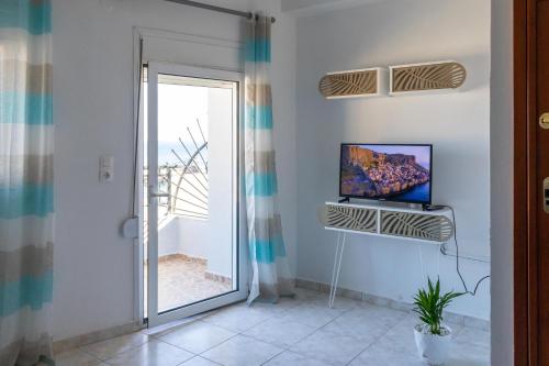 a living room with a tv and a sliding glass door at Lovely sea view apartment at the heart of the town in Ierápetra