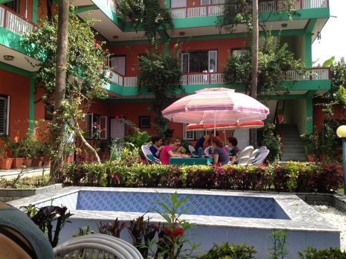 a group of people sitting at a table under an umbrella at New Pokhara Lodge and Home Stay in Pokhara