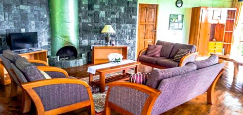 a living room with a couch and chairs and a fireplace at Mesilau Mountain Retreats in Kundasang