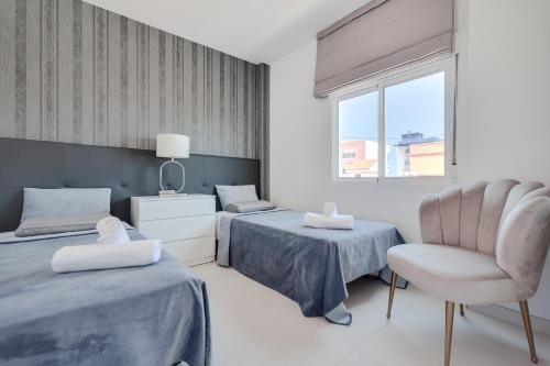 a bedroom with two beds and a chair and a window at Doris 2 in Gandía