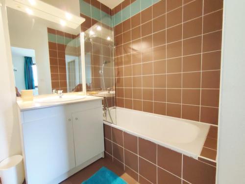 uma casa de banho com uma banheira, um lavatório e um espelho. em Chez Marie-Laure, T3 résidence les Jardins de Ramel, parking, balcon, 4 personnes em Luchon