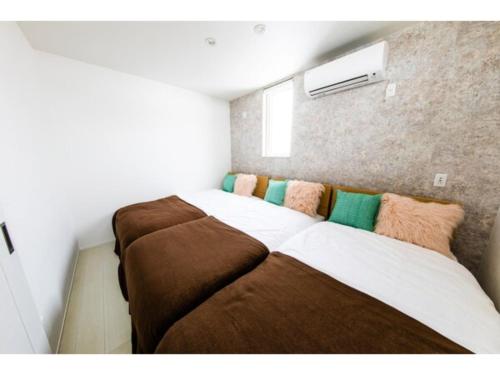 um quarto com 2 camas com almofadas castanhas e verdes em Terrace Toyohira / Vacation STAY 81233 em Sapporo