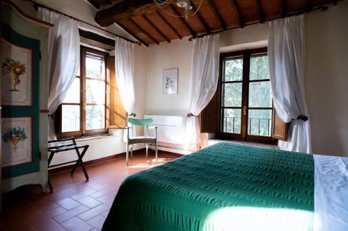 a bedroom with a green bed in a room with windows at Relais Riserva di Fizzano in Castellina in Chianti