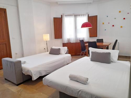 a room with two beds and a table and a desk at Apartamentos Catedral Plaza 3000 in Granada