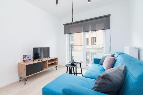 um sofá azul numa sala de estar com uma televisão em Lwowska 10 Residence Apartment Cracow em Cracóvia