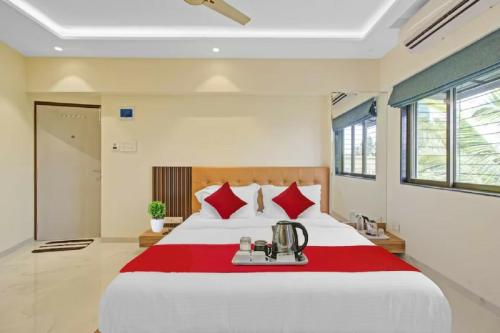 a bedroom with a large bed with red pillows at Hotel Sunrise Juhu in Mumbai