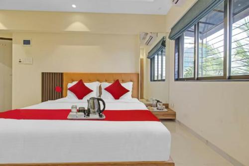 a bedroom with a large white bed with red pillows at Hotel Sunrise Juhu in Mumbai