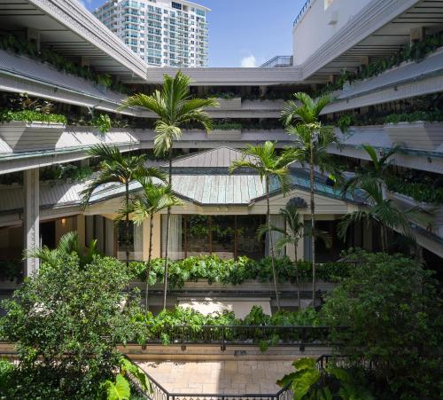 an apartment building with a courtyard with palm trees at Mayfair House Hotel & Garden in Miami