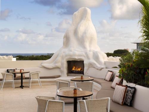 a patio with a fireplace and tables and chairs at Mayfair House Hotel & Garden in Miami