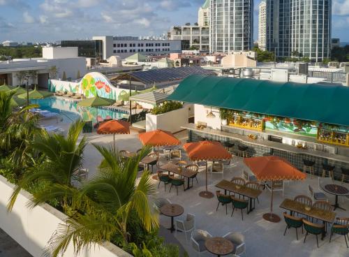an outdoor patio with tables and umbrellas and a pool at Mayfair House Hotel & Garden in Miami