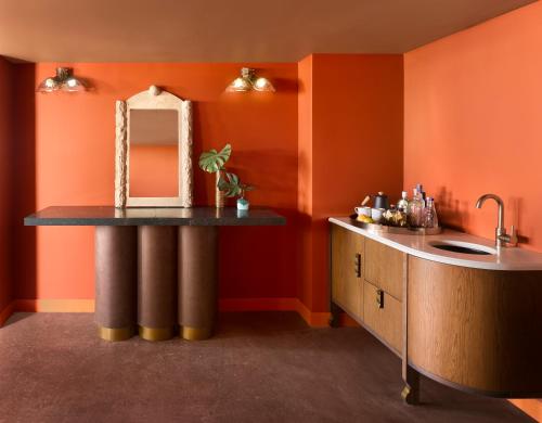 Łazienka z pomarańczowymi ścianami, umywalką i lustrem w obiekcie Mayfair House Hotel & Garden w Miami