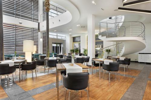 restauracja ze stołami i krzesłami oraz spiralnymi schodami w obiekcie Hotel Moderno Poznań w Poznaniu