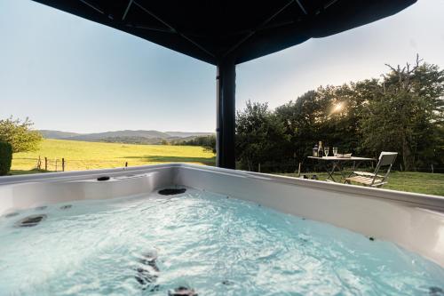 a hot tub with a view of a field at Roulotte Paradis: insolite, SPA privatif, piscine in Chilly