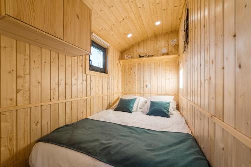 a bed in the corner of a wooden cabin at Roulotte Paradis: insolite, SPA privatif, piscine in Chilly