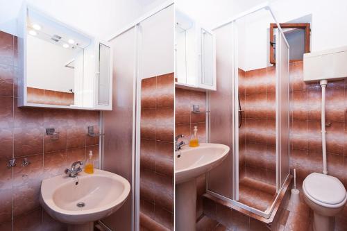 a bathroom with two sinks and a toilet and a mirror at Apartments by the sea Cove Saplunara, Mljet - 12849 in Maranovići