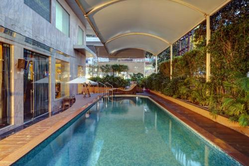 a swimming pool in a building with an umbrella at Mosaic Hotel, Noida in Noida