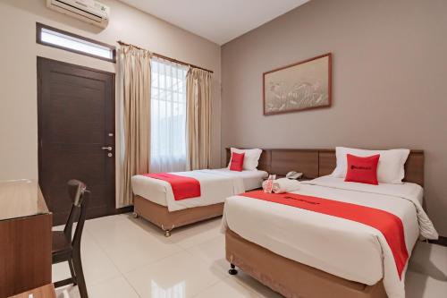 a bedroom with two beds with red and white sheets at RedDoorz near Simpang Dago 2 in Bandung
