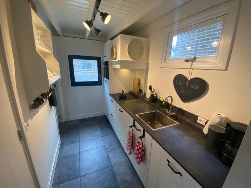 uma pequena cozinha com um lavatório e uma janela em Gastenverblijf op de Prins Hendrik Hoeve in Buren em Buren