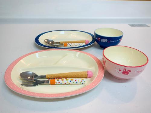 a table with a plate with a fork and a cup at Sunset Beach Vacation House in Chatan