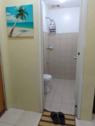 y baño con ducha, aseo y alfombra. en Affordable Staycation along Ortigas Extension, en Cainta