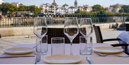 einen Tisch mit vier Weingläsern und Tellern darauf in der Unterkunft Apartamento Luxury Triana-Los Remedios in Sevilla