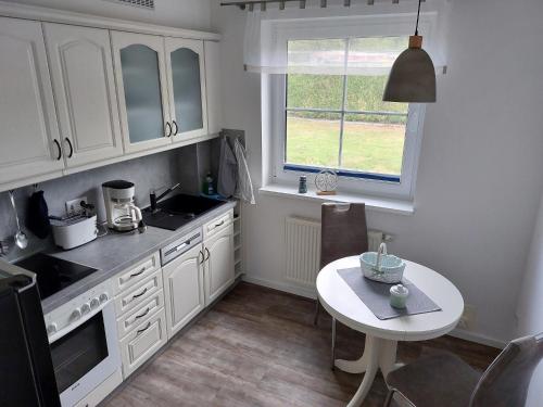a kitchen with white cabinets and a table and a window at Ferienwohnung Finja - a70682 in Dreschvitz