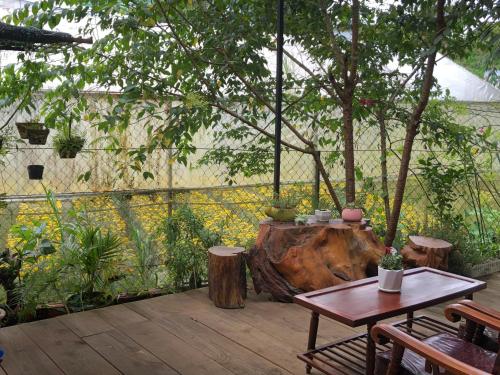 a wooden deck with a table and a tree at Nhà Bắp in Da Lat