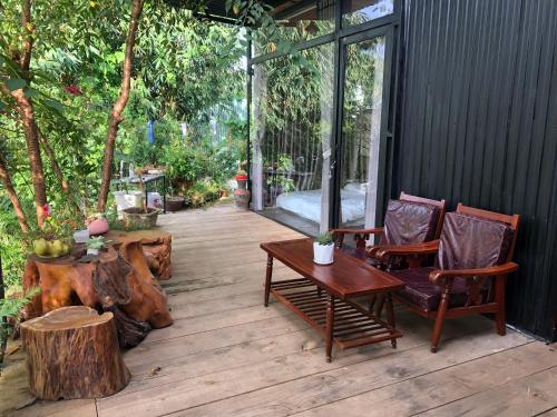 a patio with two chairs and a table and trees at Nhà Bắp in Da Lat