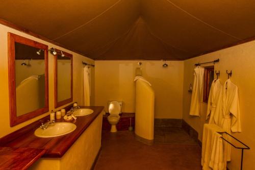 a bathroom with two sinks and a toilet in it at Elewana Lewa Safari Camp in Meru