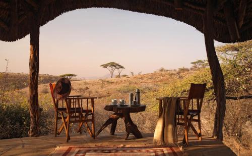 a table and chairs on a porch of a tent at Elewana Lewa Safari Camp in Meru