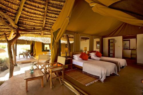 Elewana Lewa Safari Camp في Meru: غرفة نوم بسريرين في خيمة