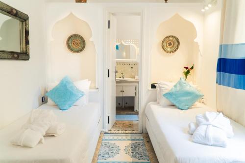 two beds in a room with white walls and blue pillows at Dar Liouba Hotel in Essaouira