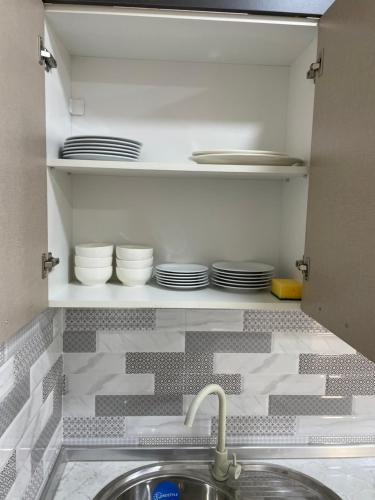 a kitchen with a sink and plates on a shelf at Kvartira in Quba