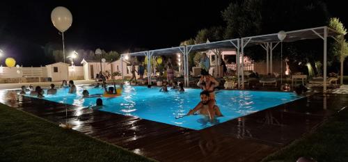 un gruppo di persone in una piscina di notte di Appartamenti in villa Alessia a Monopoli