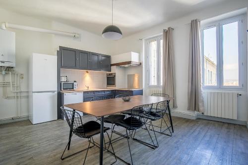 une cuisine avec une table, des chaises et un réfrigérateur dans l'établissement Superbe Appartement 6CH dans le cœur de Marseille - La French Casa Dragon, à Marseille
