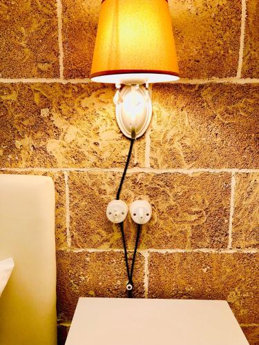 a lamp attached to a brick wall with a table at Corte Gabellone - dimora storica in Nardò